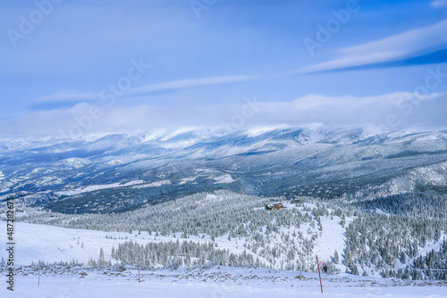 Beautiful view of Colorado mountain range after snowfall; chairlift and building at distance