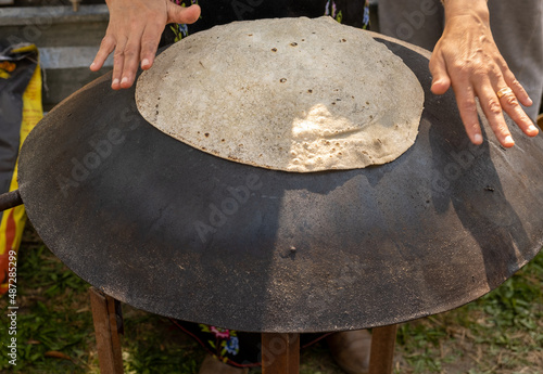 Arabian female person prepare flatbread (other names is pita, lavash, lafa, roti, chapati) on hot saj