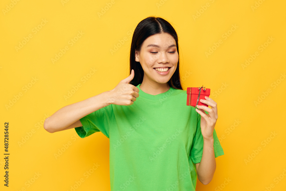 Charming young Asian woman with a small gift box holiday isolated background unaltered Charming young Asian woman with a small gift box holiday isolated background unaltered