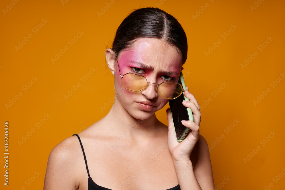 Obraz premium Portrait of beautiful young woman with a phone in hand bright makeup posing fashion emotions close-up unaltered