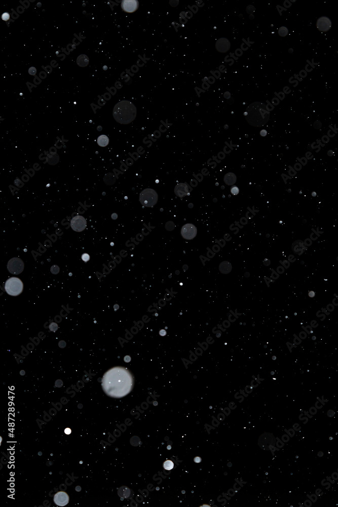 Real falling white snow against black night sky in the winter. Snowing at dark. Bokeh, multi-layered effect. Real falling white snow against black night sky in the winter. Snowing at dark. Bokeh, multi-layered effect.