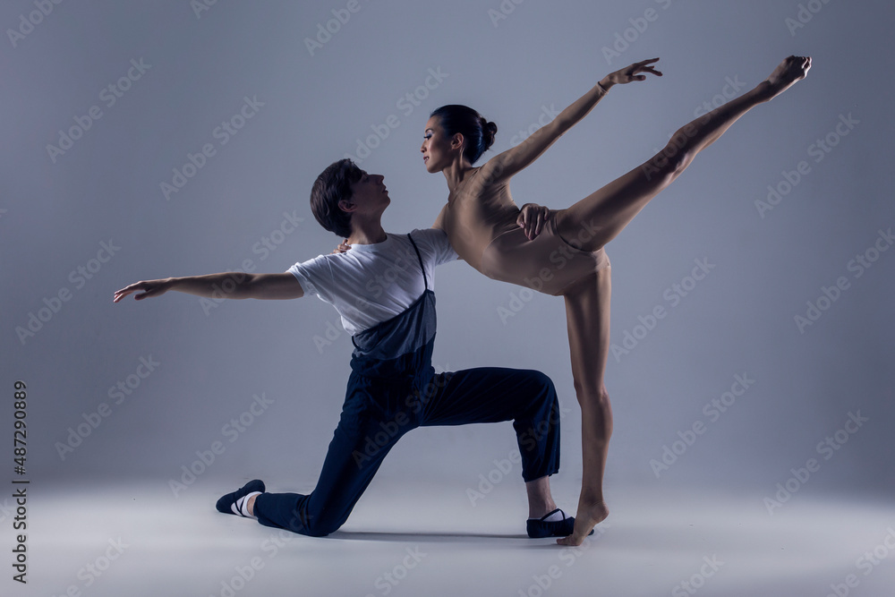 Fototapeta premium Dance Photography. Professional Ballet Dance Couple Performing Together in Studio While Girl Posing in Bodysuit Against White Background.