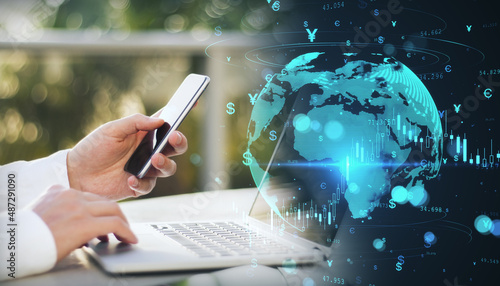 Foto Close up of businessman hands using laptop computer and smartphone with glowing money transfer globe on blurry background