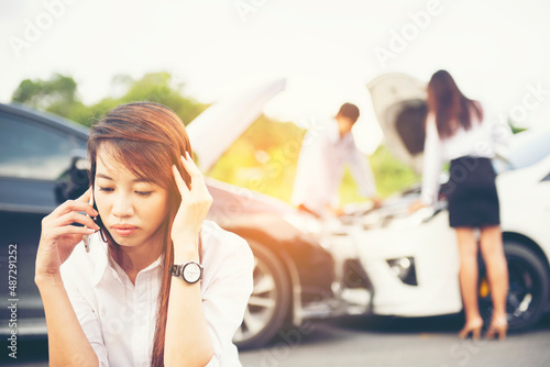 Asia Woman Beautiful young woman driver calls with smartphone for instruction during insurance agent review the dammage of the car after accident photo