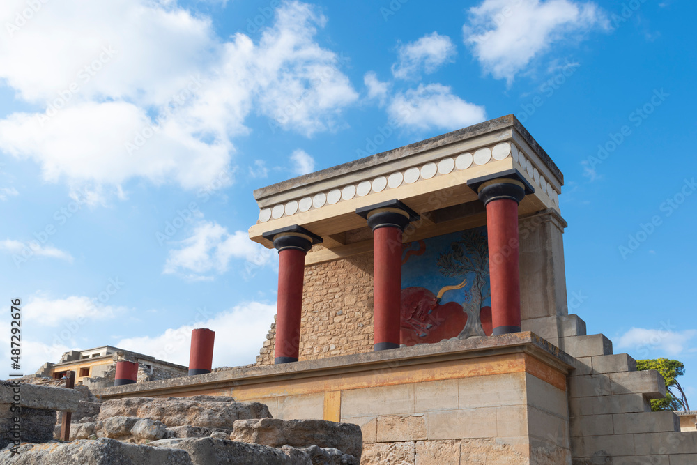Minoan palace Knossos at Heraklion, Crete island, Greece. North Entrance with charging bull fresco and three red columns against cloudy sky