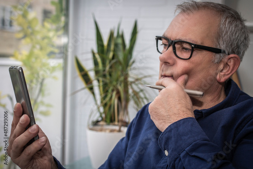 adult man with presbyopia or tired eyes consulting the phone at home