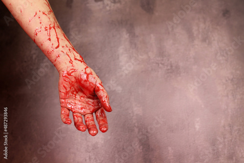 Bloody hand of the victim of a maniac, a murderer on a gray background. Copy space for text