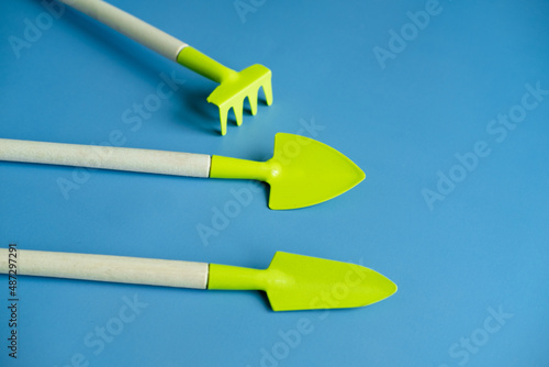 bright green shovel and rake on a blue background top view. Banner. copy spices. flat lay