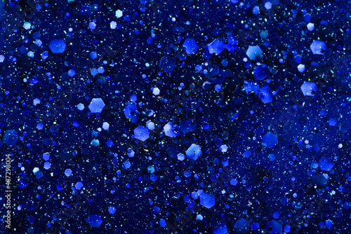 Top flat view on beautiful shimmering texture of liquid blue glitter nail polish. Blue nail polish close-up texture.