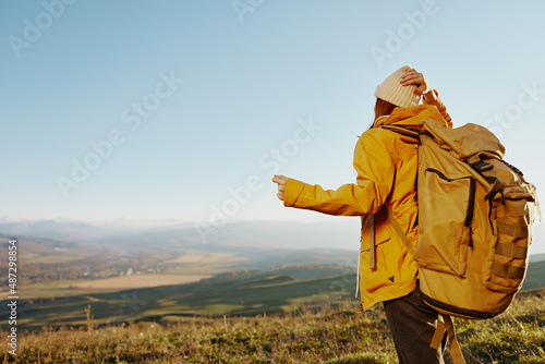 woman in a yellow jacket in a hat backpack travel mountains Fresh air