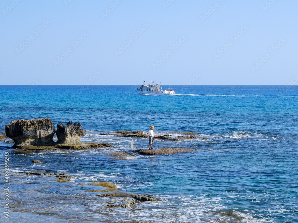 fisherman catches fish on the rocky seashore