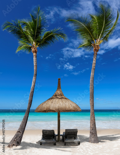 Chairs and umbrella in sunny tropical Palm Beach and turquoise sea. Summer vacation and tropical beach concept. 