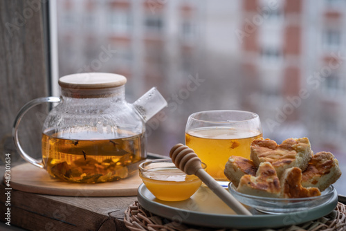 composition with a glass teapot and glass cup filled with tea and cake on the plate