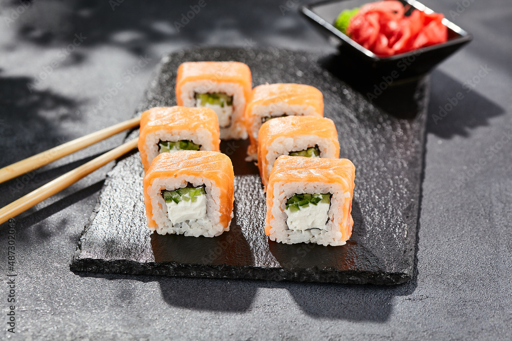Maki sushi on dark stone table. Philadelphia maki with salmon. Sushi
