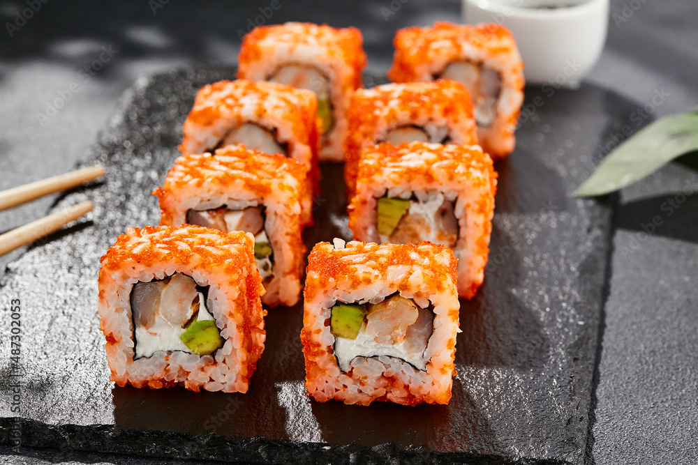 Maki sushi on dark stone table. California maki with tobiko. Sushi roll