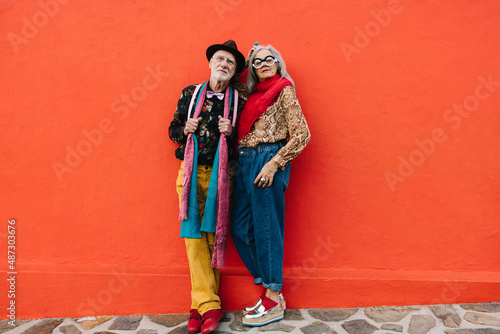 Mature couple standing together against a red wall