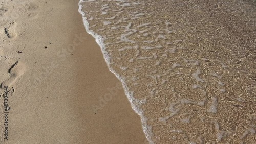 Gentle sea wave on the shore of a sandy beach. Slow motion