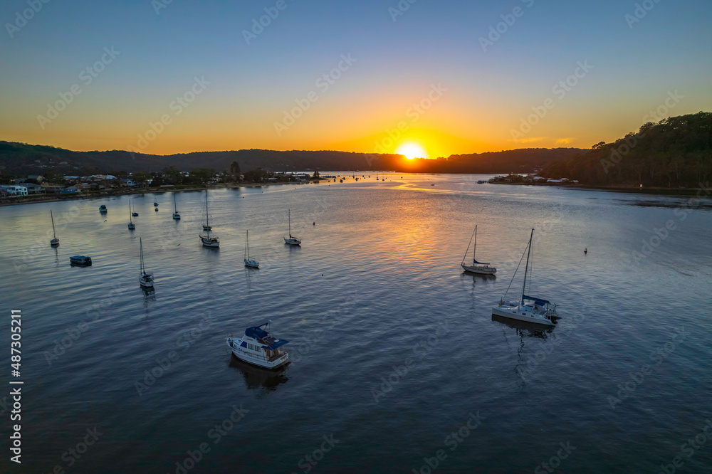 Naklejka premium Aerial sunrise waterscape with boats and clear skies