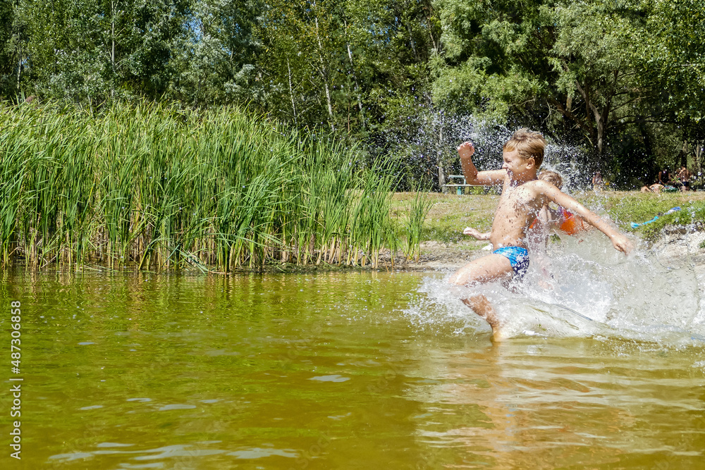 little boy bathes near the shore in a forest lake, summer little boy bathes near the shore in a forest lake, summer