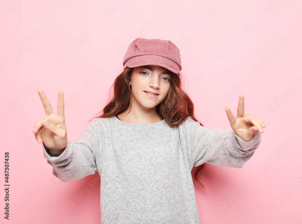 Close-up portrait of child girl laughing with toothy smile and show v-sign over pink background. Close-up portrait of child girl laughing with toothy smile and show v-sign over pink background.