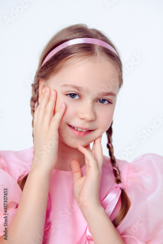 A beautiful cheerful little girl about 10 years old in a beautiful dress on an isolated white background.A place for your text.