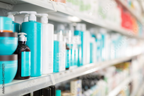 Plastic bottles of various hair care products on shelves of cosmetics store
