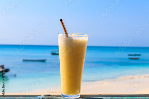 Glass of fresh juice by the ocean. Tropical vacations concept
