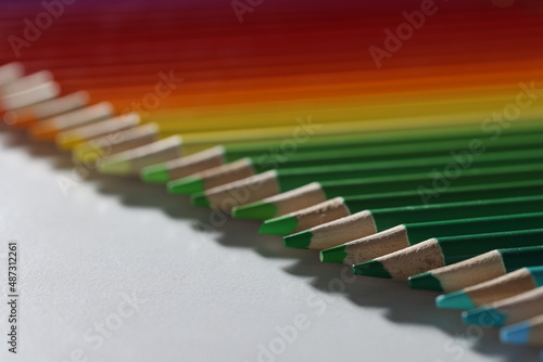 Colored pencils lie in a row on the table  blurry