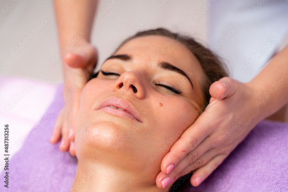 Relaxing massage. European woman getting facial massage in spa salon, side view Relaxing massage. European woman getting facial massage in spa salon, side view