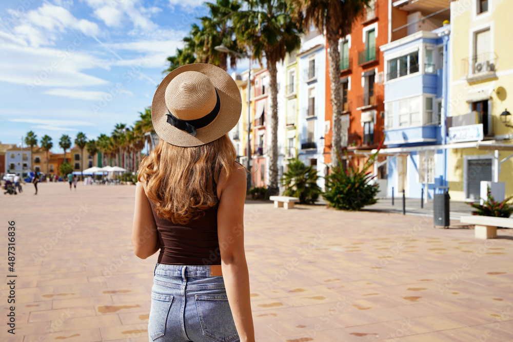 Holidays in Europe. Happy traveler girl visiting the colorful Spanish village with palm trees and beaches Villajoyosa, Alicante, Spain. Copy space.