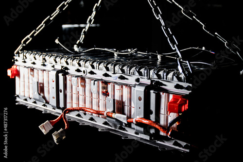 Large assembly of EV battery cells on their own steel subframe. The frame shows the wires for the unit's BMS, as well as the wiring for temperature sensors and power terminals. Selective focus