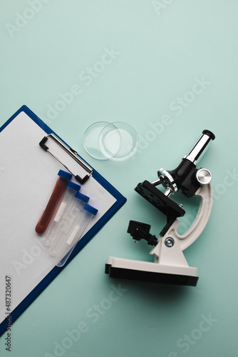 Microscope, test tubes and watch glass on a blue background. Laboratory or analysis theme. Vertical image