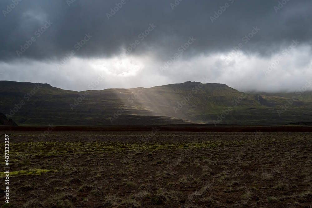 Nur wenige Sonnenstraheln dringen durch hängende Regenwolken im Hítardalur am Berg Fagraskógarfjall auf der Halbinsel Snæfellsnes