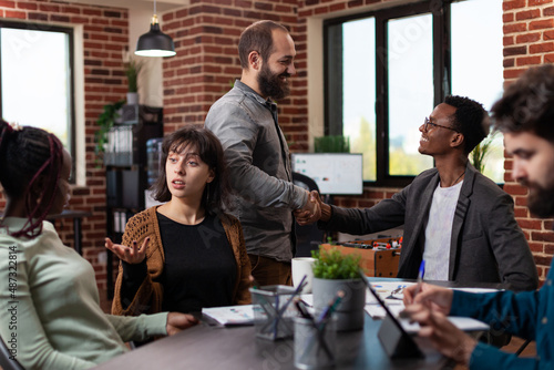 Businessman shaking hand with manager during business meeting in startup office. Multi-ethnic businesspeople discussing company turnover working at marketing strategy brainstorming ideas