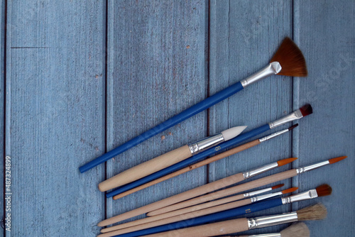 Set of artistic paintbrushes on blue background.