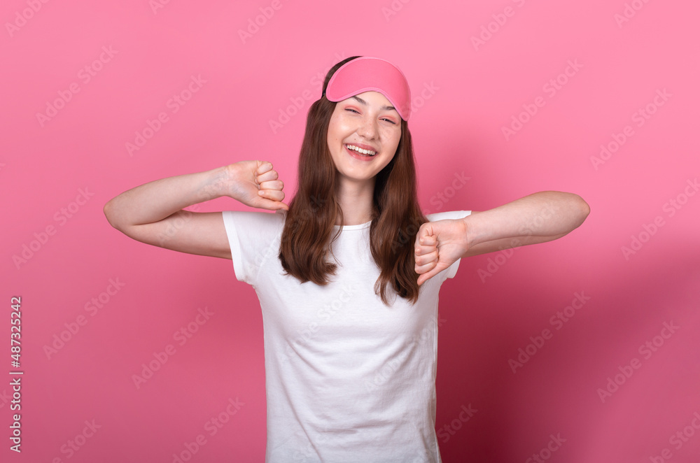 lovely sleepy smiling caucasian brunette teen girl awake stretching hands after night dream wear sleep mask and white t-shirt isolated on pink background good morning concept lovely sleepy smiling caucasian brunette teen girl awake stretching hands after night dream wear sleep mask and white t-shirt isolated on pink background good morning concept