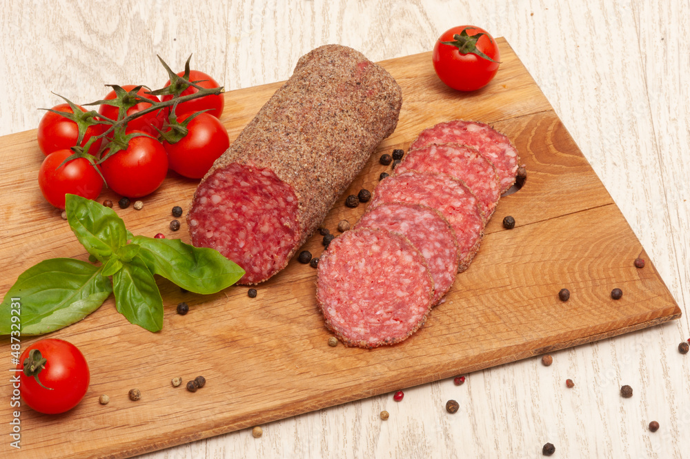 Sausage on a wooden board with cherry tomatoes and basil Sausage on a wooden board with cherry tomatoes and basil