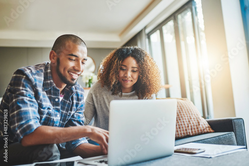 Managing money matters with wireless technology. Shot of a young couple using a laptop while working on their home finances.