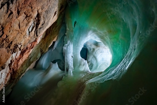 Ice Formations in a big ice cave “Eisriesenwelt“ in the austrian alps is a tourist attraction near Salzburg and Werfen with green reflections in the frozen waterfall underground and limestone rock photo