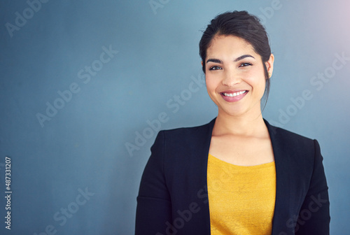 Confidence is the key to success. Studio portrait of an attractive young businesswoman standing against a blue background. photo