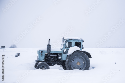 Tractor on a snow-covered field against a cloudy sky.