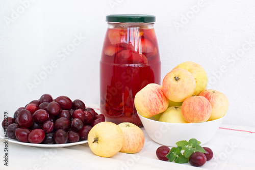 Fotografie plums, yellow apples and compote on a light background