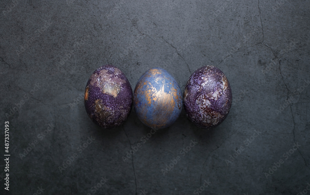 Easter card with a copy of the place for the text. Purple, blue and golden eggs on a dark background. The trend of 2022 purple shade is very peri. Natural dye karkade tea. Top view. Easter card with a copy of the place for the text. Purple, blue and golden eggs on a dark background. The trend of 2022 purple shade is very peri. Natural dye karkade tea. Top view.