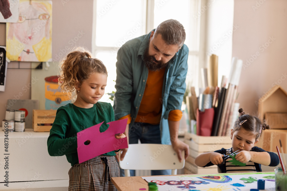 Fototapeta premium Little kids working on project with teacher during creative art and craft class at school.