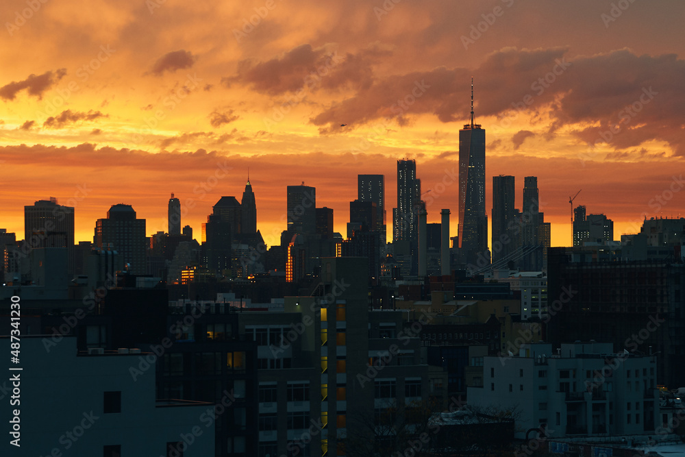 New York Lower Manhattan sunset skyline view from Brooklyn with dramatic sky and clouds over roofs