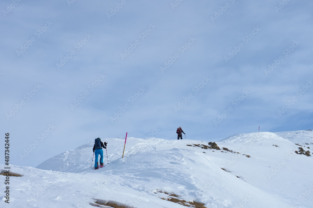 Snowshoe hikers on a marked trail towards mount Darlux in Berguen, Switzerland