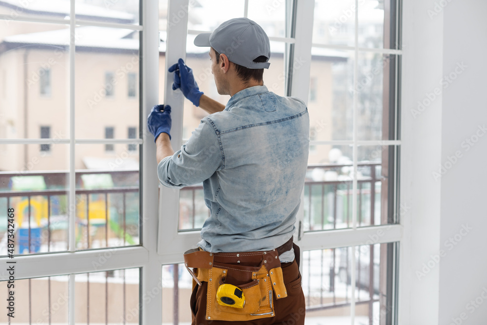 Construction worker installing window in house. Handyman fixing the window with screwdriver Construction worker installing window in house. Handyman fixing the window with screwdriver