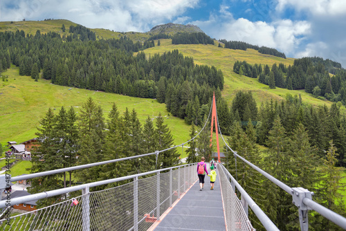 Frau mit Kind wandert über Hängeseilbrücke im Talschluss bei Saalbach Hinterglemm in Österreich photo