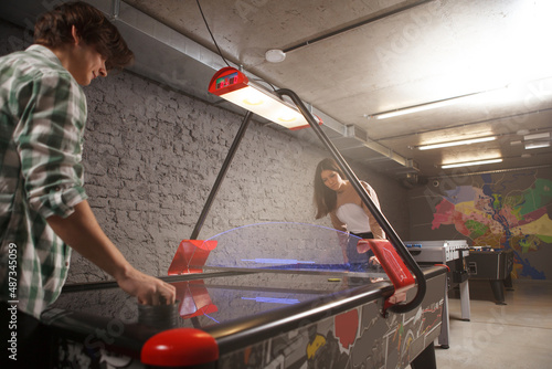 Low angle shot of a young couple playing on air hockey table, copy space photo