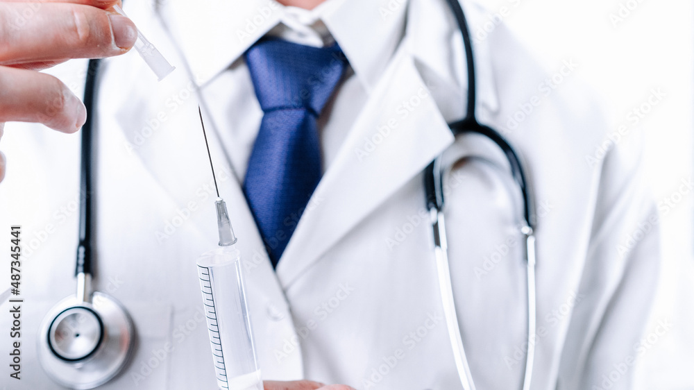 Syringe needle medical injection. Selective focus, doctor hand in blue gloves holding syringe with needle. Hospital white doctor gown, stethoscope. Syringe with flu vaccine with copy space. Syringe needle medical injection. Selective focus, doctor hand in blue gloves holding syringe with needle. Hospital white doctor gown, stethoscope. Syringe with flu vaccine with copy space.
